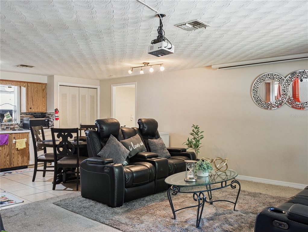 A living room features a projector, black leather recliner, and a glass coffee table — 613 S WILLOW AVENUE, AVON PARK, FL