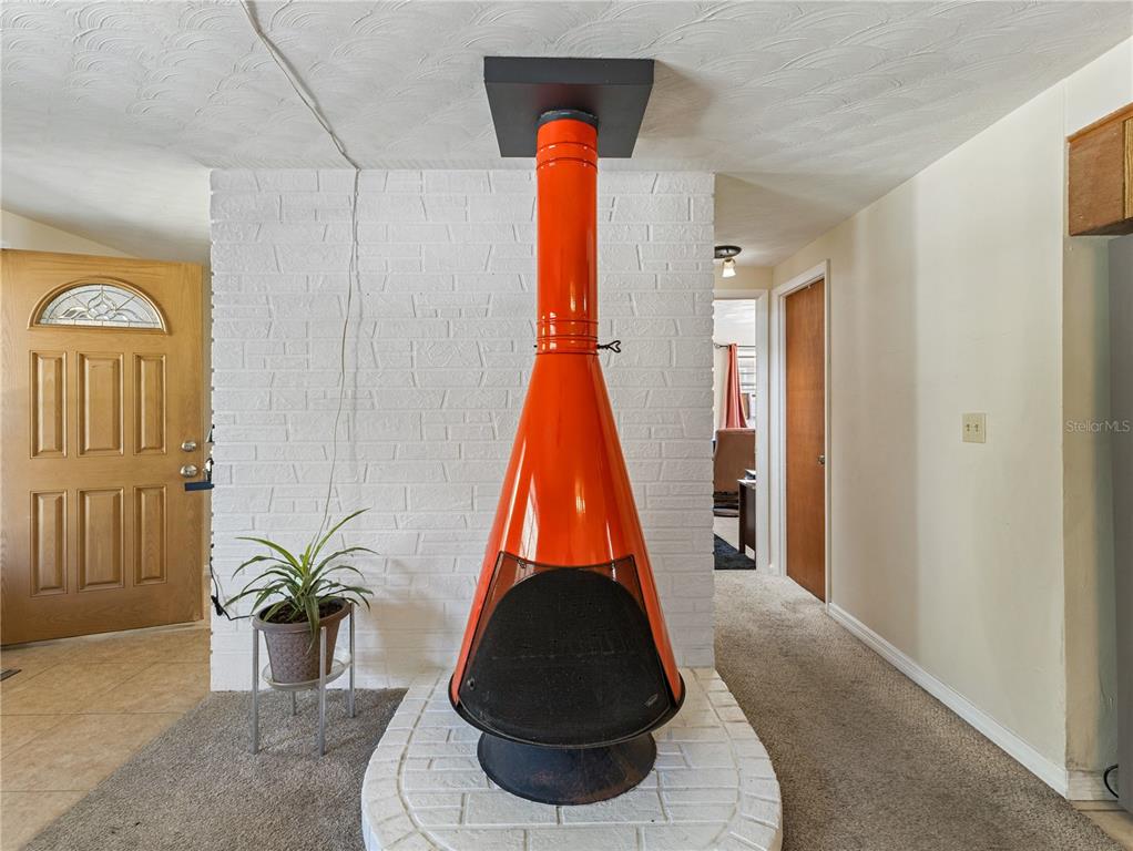 A bright orange mid-century modern fireplace stands before a white painted brick wall — 613 S WILLOW AVENUE, AVON PARK, FL