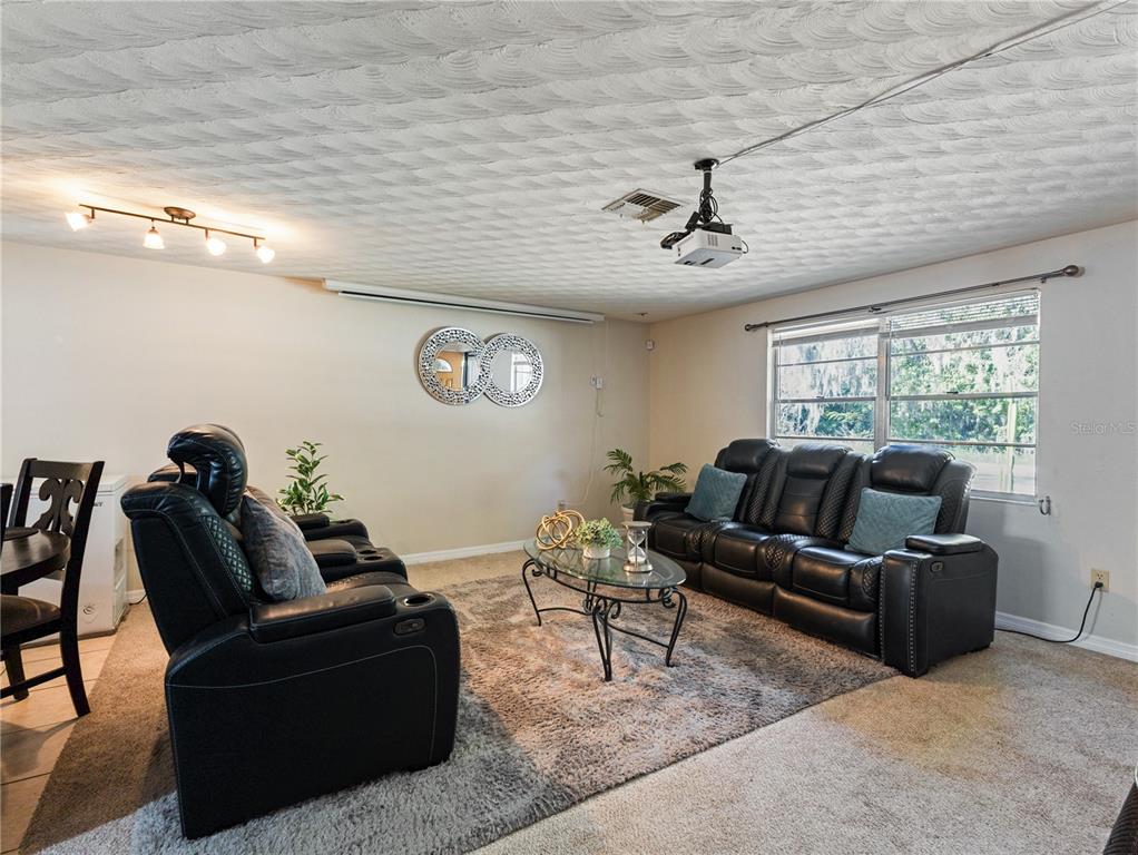 A living room features black leather recliners, a glass coffee table, and a ceiling-mounted projector — 613 S WILLOW AVENUE, AVON PARK, FL
