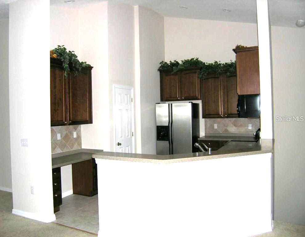 A kitchen with dark wood cabinets, stainless steel appliances, and a breakfast bar — 27802 PLEASURE RIDE LOOP, WESLEY CHAPEL, FL