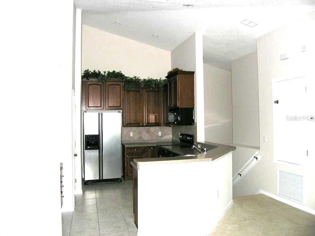 A kitchen with dark wood cabinets, stainless steel appliances, and a peninsula counter — 27802 PLEASURE RIDE LOOP, WESLEY CHAPEL, FL