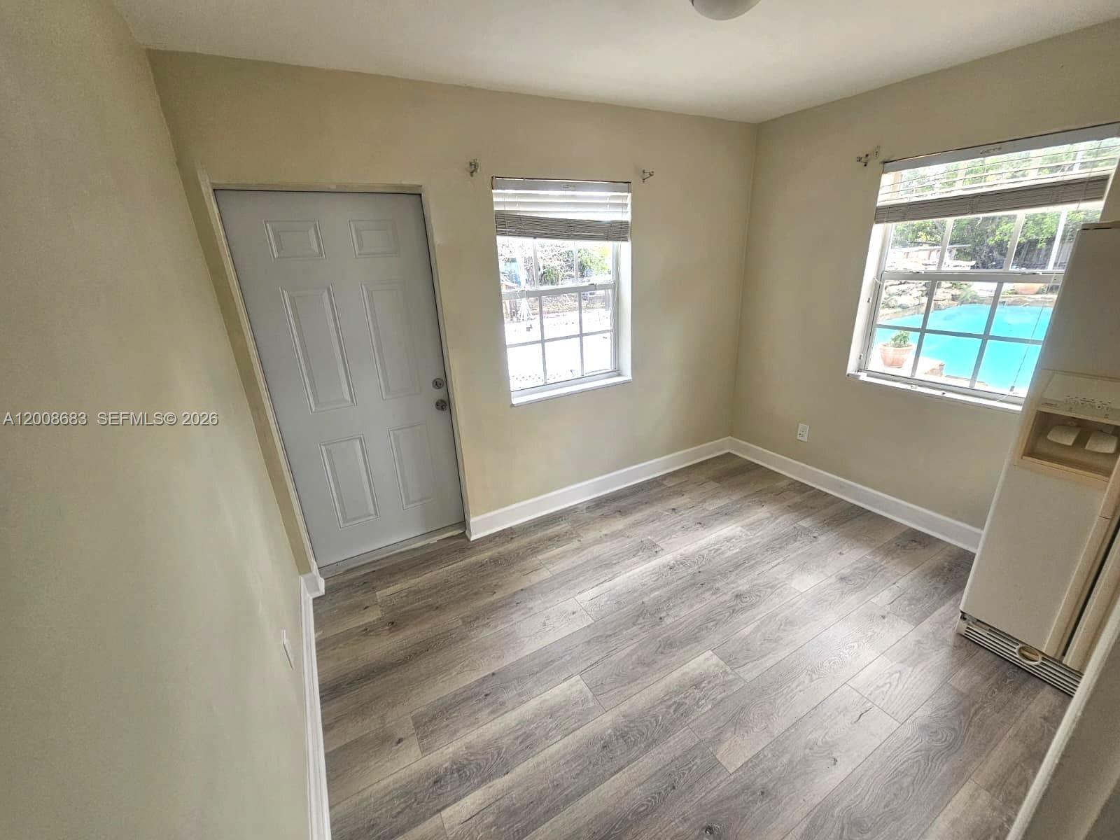 A room with light-colored walls, wood-look flooring, two windows, a door, and a wall unit — 10790 SW 46th St # 10790, Miami FL 33165, MIAMI, FL