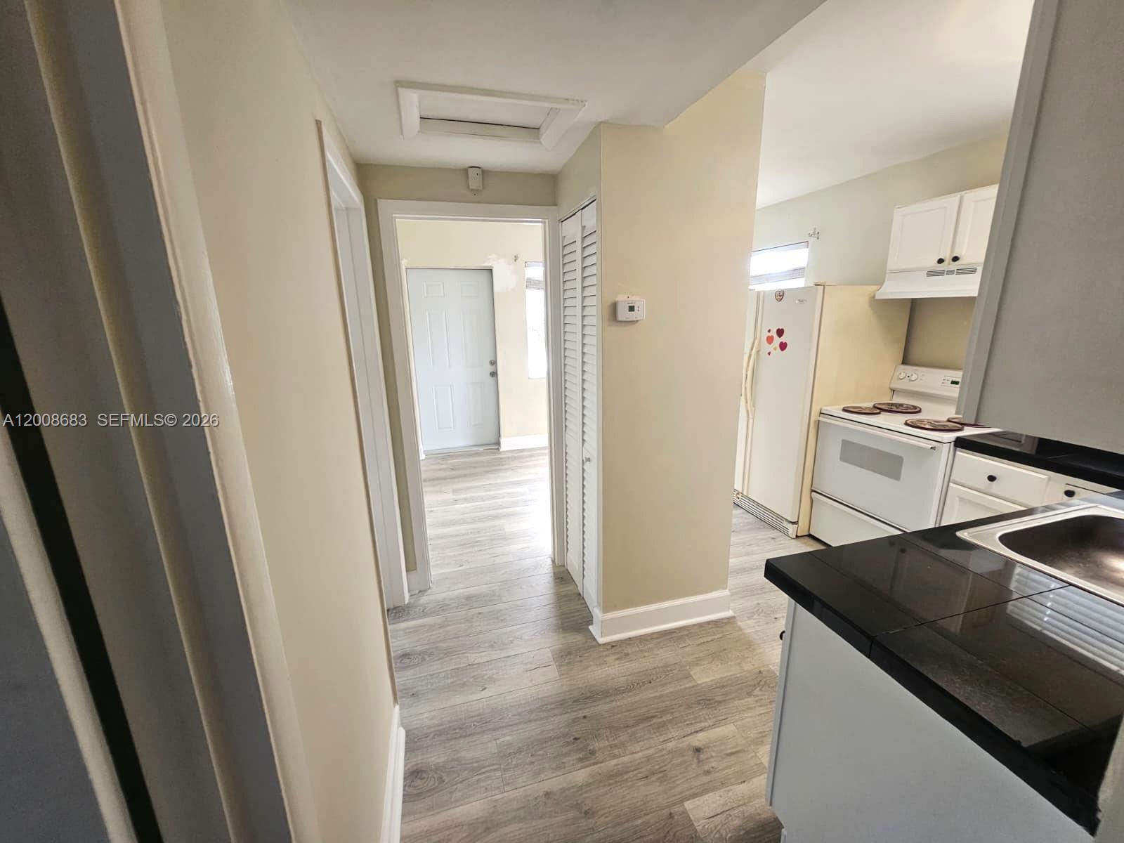 A view from a kitchen with black countertops looking toward a hallway and exterior door — 10790 SW 46th St # 10790, Miami FL 33165, MIAMI, FL