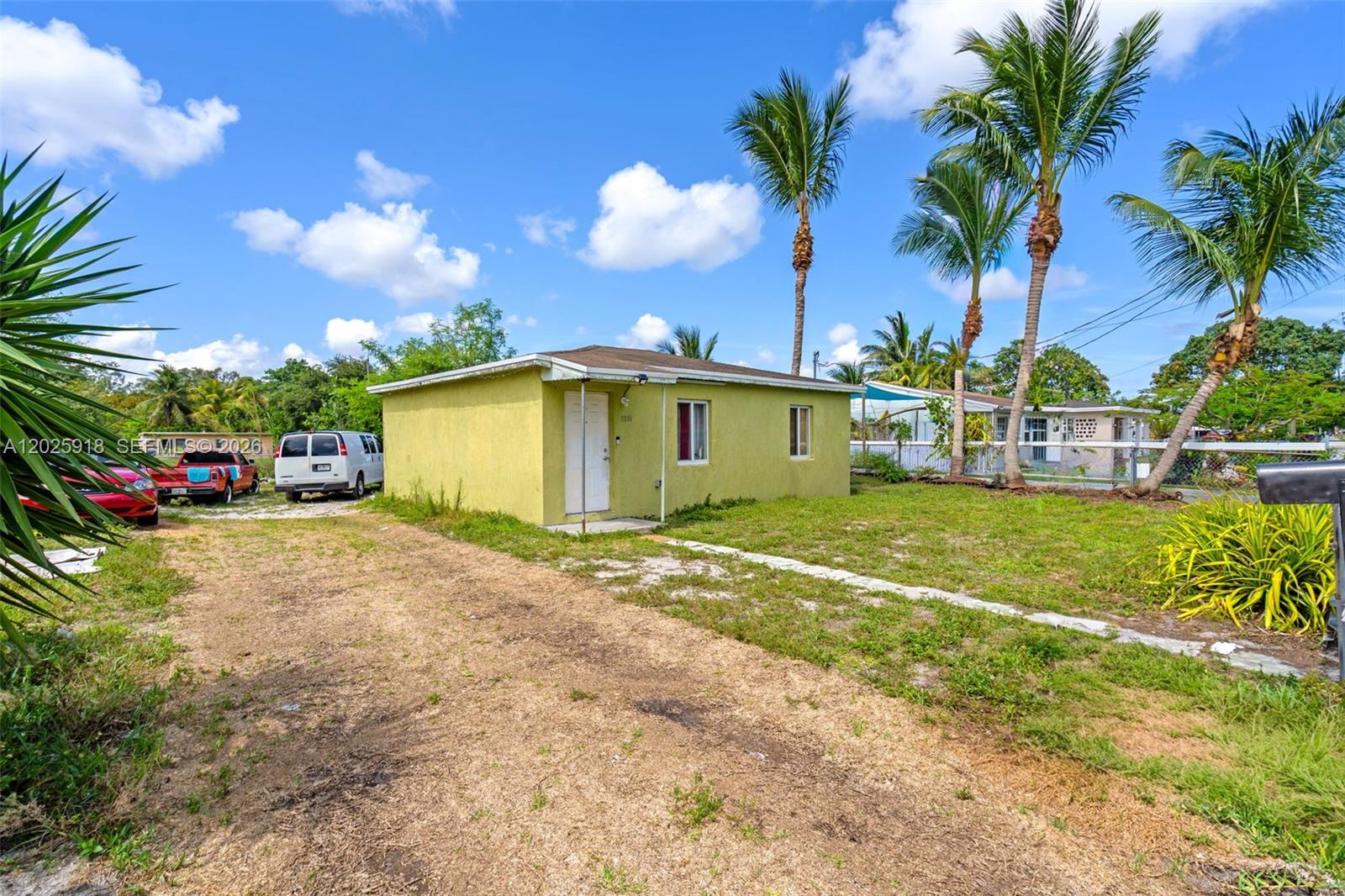 A small, yellow, single-story house sits on a grassy lot with palm trees and vehicles — 2365 NW 155th St, Miami Gardens FL 33054, MIAMI GARDENS, FL