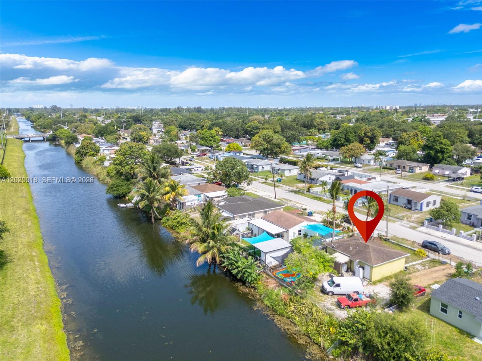 An aerial view shows a yellow house with a red pin next to a canal — 2365 NW 155th St, Miami Gardens FL 33054, MIAMI GARDENS, FL