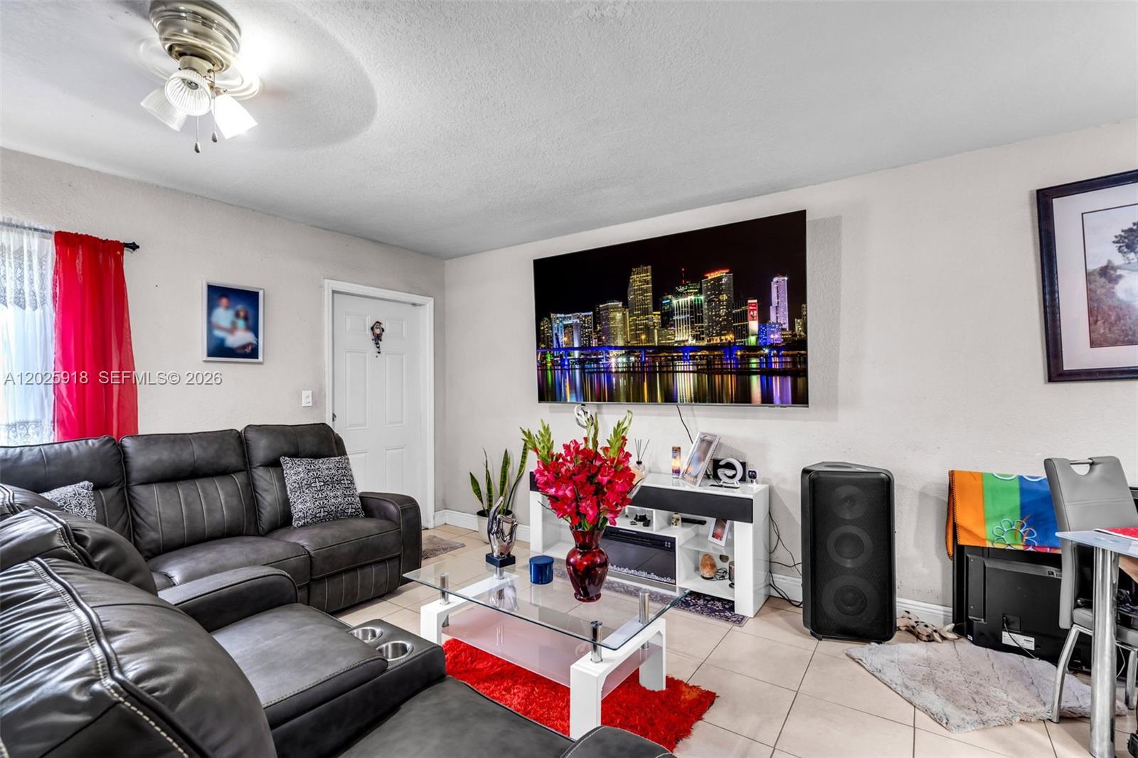 A living room features a dark leather sectional, a glass coffee table, and a wall-mounted television — 2365 NW 155th St, Miami Gardens FL 33054, MIAMI GARDENS, FL