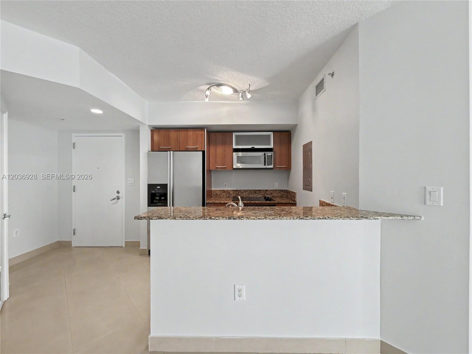 A kitchen features wood cabinets, granite countertops, stainless steel appliances, and a breakfast bar — 9055 SW 73rd Ct # 1004, Pinecrest FL 33156, PINECREST, FL