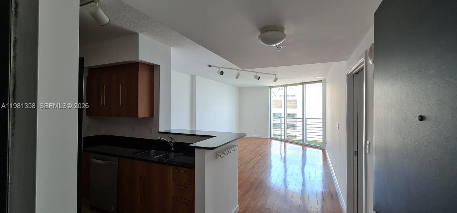 This kitchen features dark wood cabinets and black countertops, opening into a living area — 335 S Biscayne Blvd # 3610, Miami FL 33131, MIAMI, FL