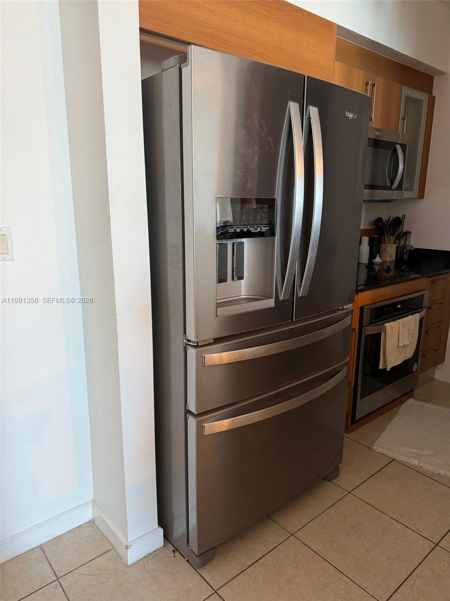 A stainless steel French door refrigerator stands in a kitchen with wood cabinets — 335 S Biscayne Blvd # 3610, Miami FL 33131, MIAMI, FL