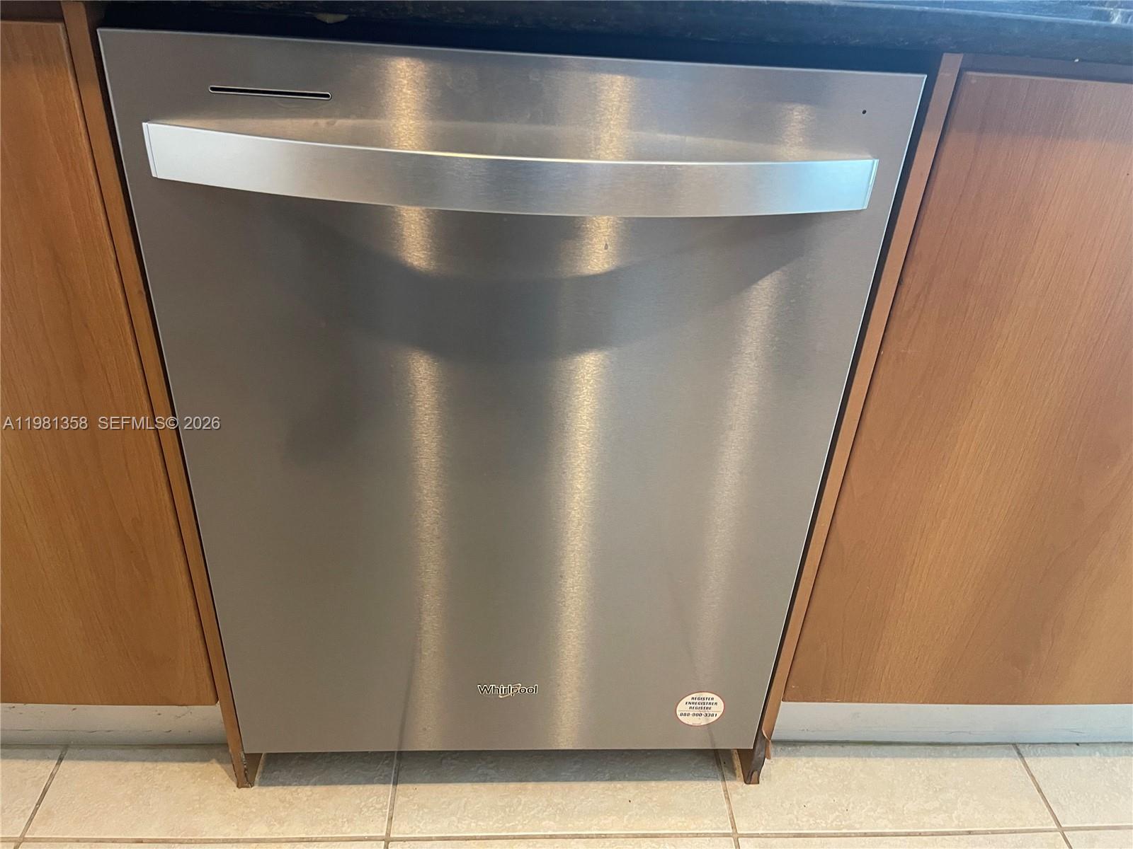 A stainless steel Whirlpool dishwasher is installed between wooden kitchen cabinets — 335 S Biscayne Blvd # 3610, Miami FL 33131, MIAMI, FL