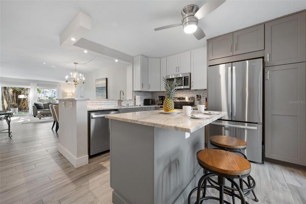 A kitchen with gray cabinets, a stone island, stainless steel appliances, and wood-look tile flooring — 5260 GULF OF MEXICO DRIVE UNIT 403, LONGBOAT KEY, FL