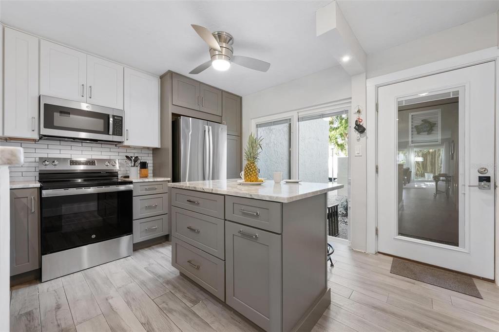 A kitchen features gray and white cabinets, stainless steel appliances, and a central island — 5260 GULF OF MEXICO DRIVE UNIT 403, LONGBOAT KEY, FL