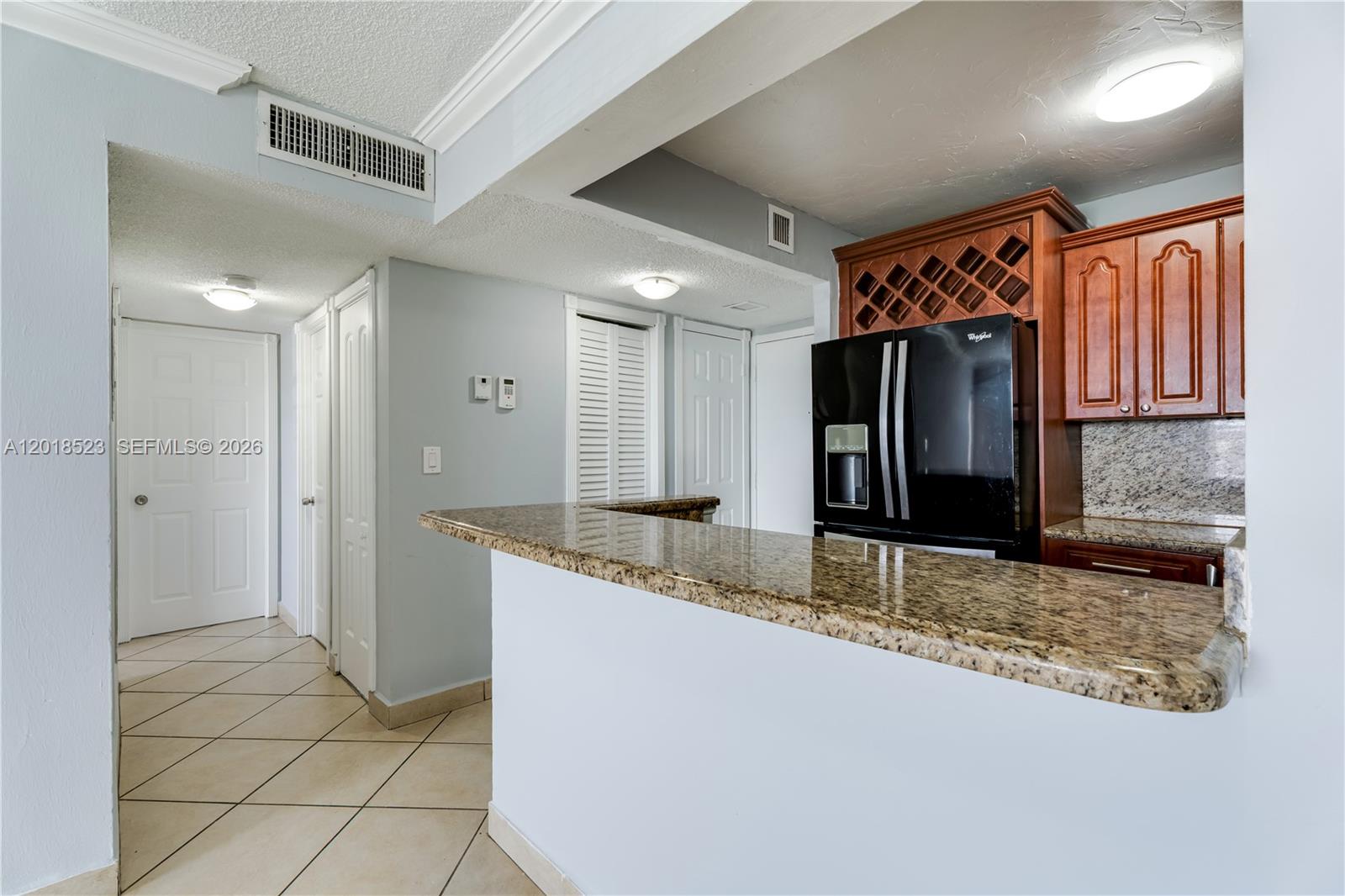 A kitchen features a granite breakfast bar, dark wood cabinets, and a black refrigerator — 5775 W 20th Ave # 404, Hialeah FL 33012, HIALEAH, FL