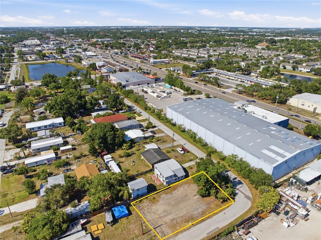 An aerial view shows a vacant rectangular lot outlined in yellow near a large warehouse — 6500 49TH WAY N, PINELLAS PARK, FL