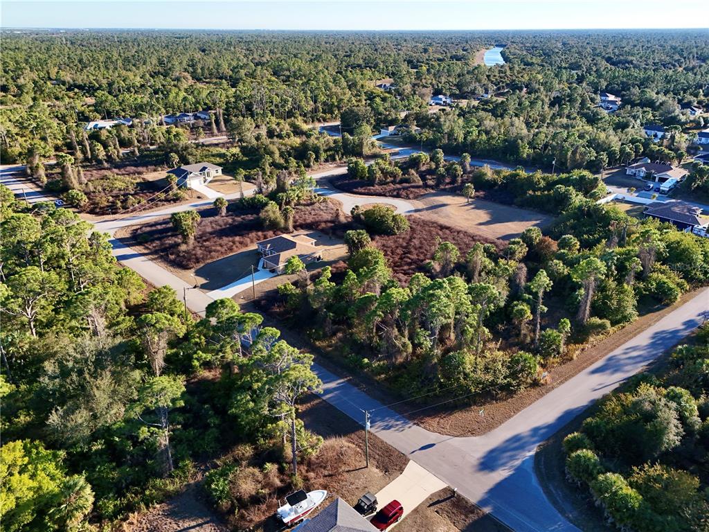 An aerial view shows a suburban neighborhood with scattered houses, paved roads, and dense vegetation — DALEWOOD CIRCLE, NORTH PORT, FL