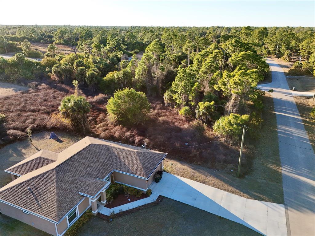 An aerial view shows a house with a shingled roof next to a vacant lot — DALEWOOD CIRCLE, NORTH PORT, FL