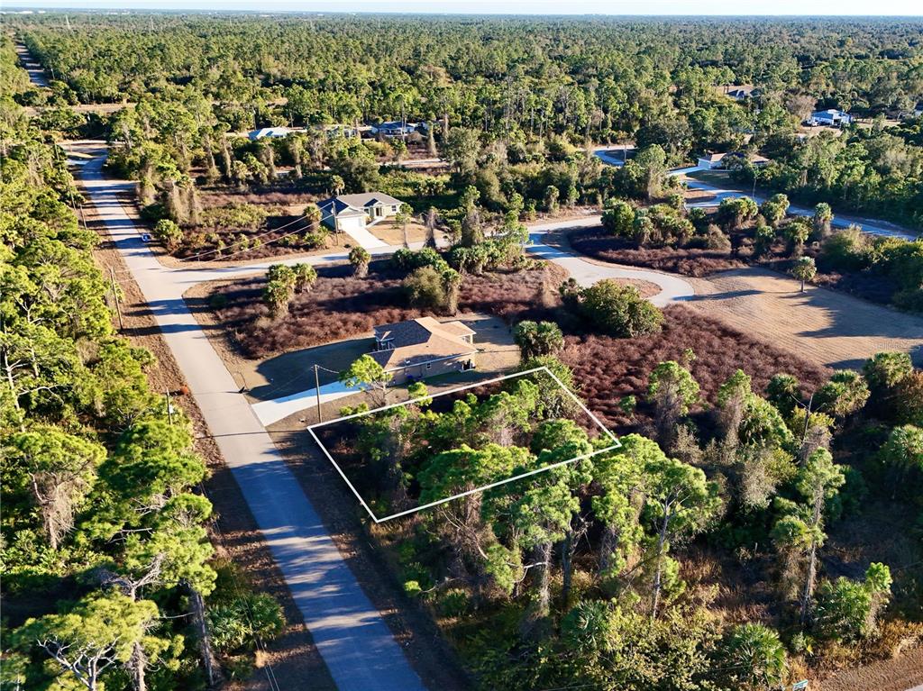 An aerial view shows a vacant, wooded residential lot outlined in white next to a house — DALEWOOD CIRCLE, NORTH PORT, FL