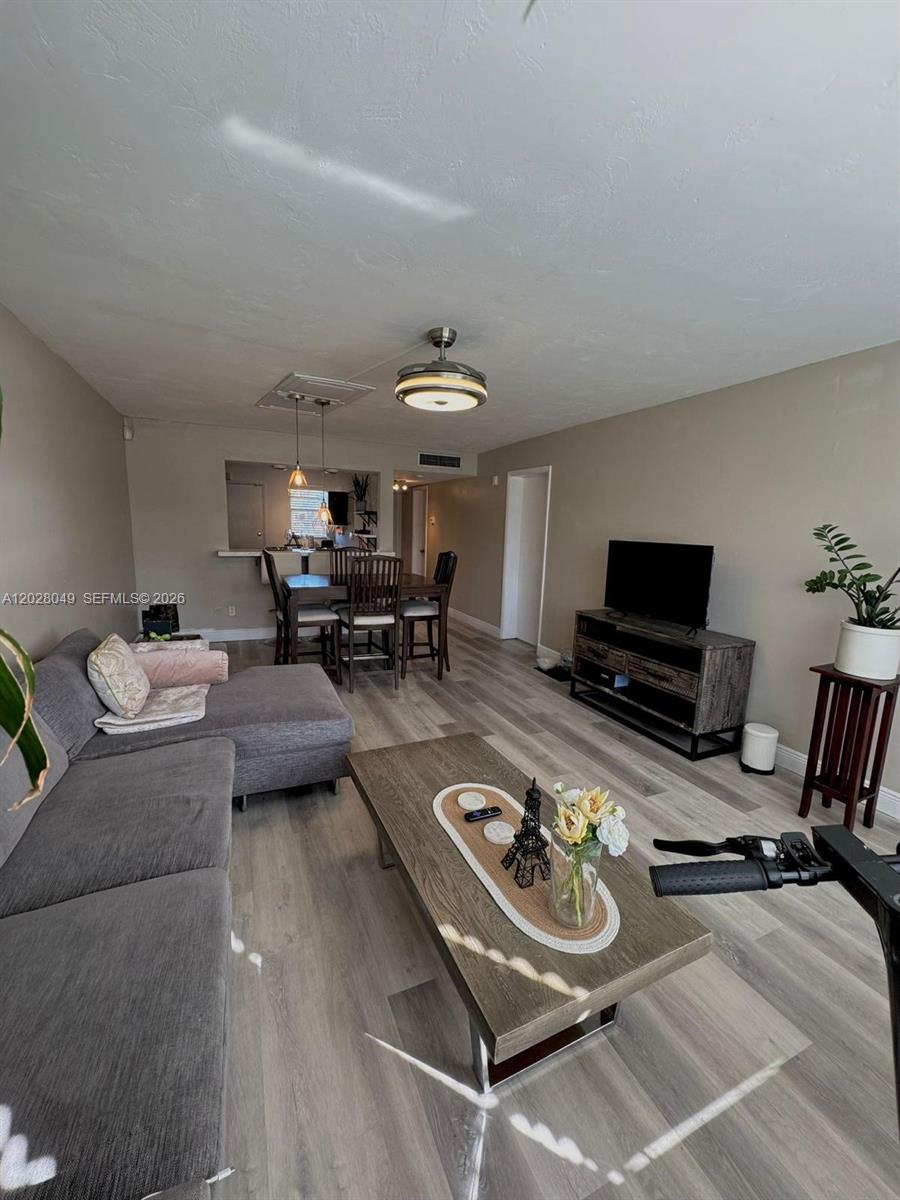 A living room features gray flooring, a sectional sofa, a coffee table, and a dining area — 1530 NE 191st St # 241, Miami FL 33179, MIAMI, FL