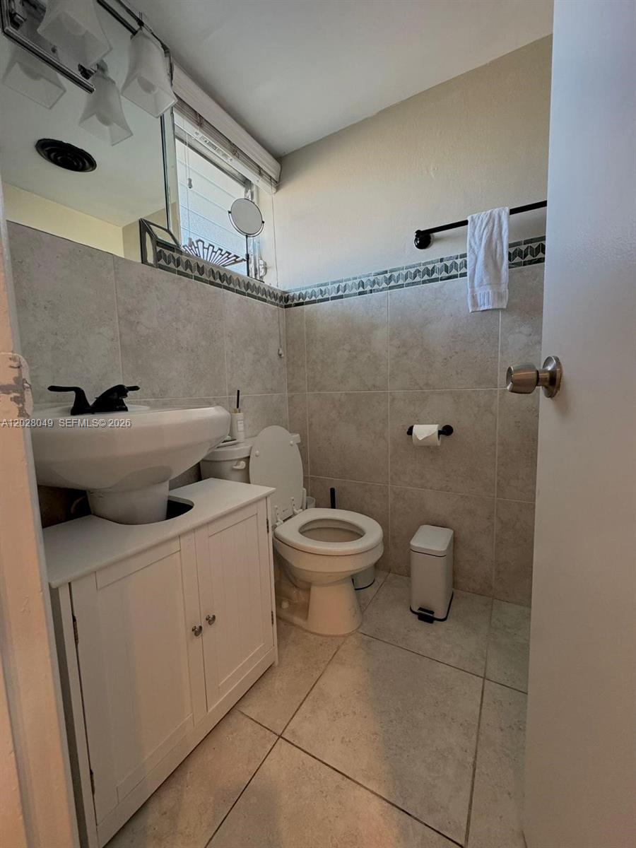 A small bathroom features a pedestal sink, a toilet, and light-colored tile walls — 1530 NE 191st St # 241, Miami FL 33179, MIAMI, FL