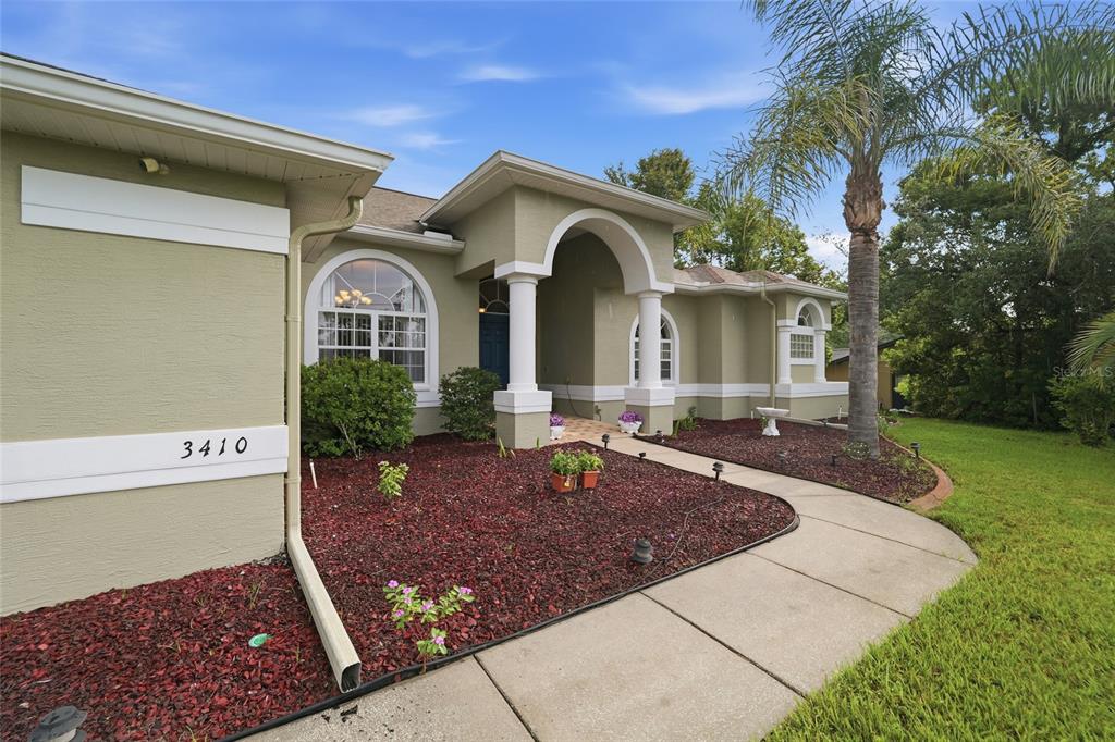 The exterior of a single-story house features a covered entryway with columns and landscaping — 3410 IRONDALE AVENUE, SPRING HILL, FL