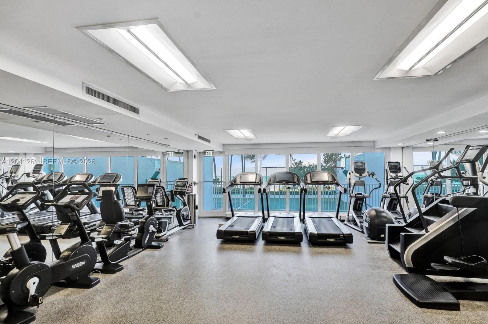 A fitness center features multiple treadmills, exercise bikes, and a stair climber with floor-to-ceiling windows — 9601 Collins Ave # 507, Bal Harbour FL 33154, BAL HARBOUR, FL