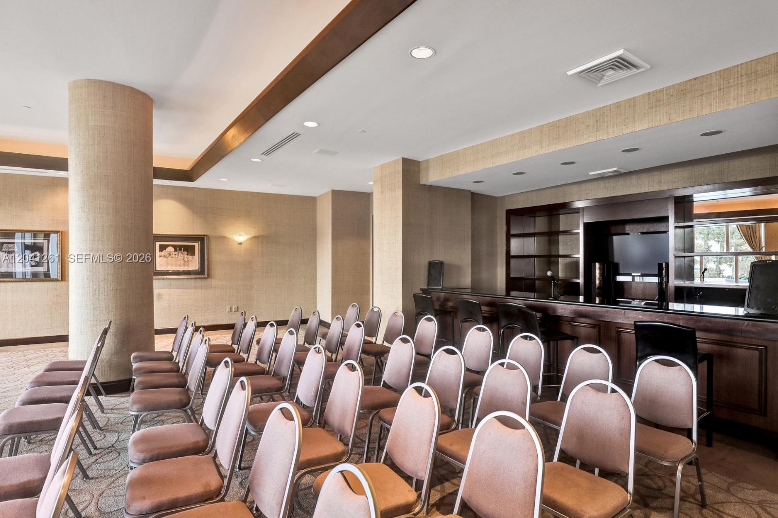 A room with rows of chairs facing a dark wood bar and shelving unit — 9601 Collins Ave # 507, Bal Harbour FL 33154, BAL HARBOUR, FL