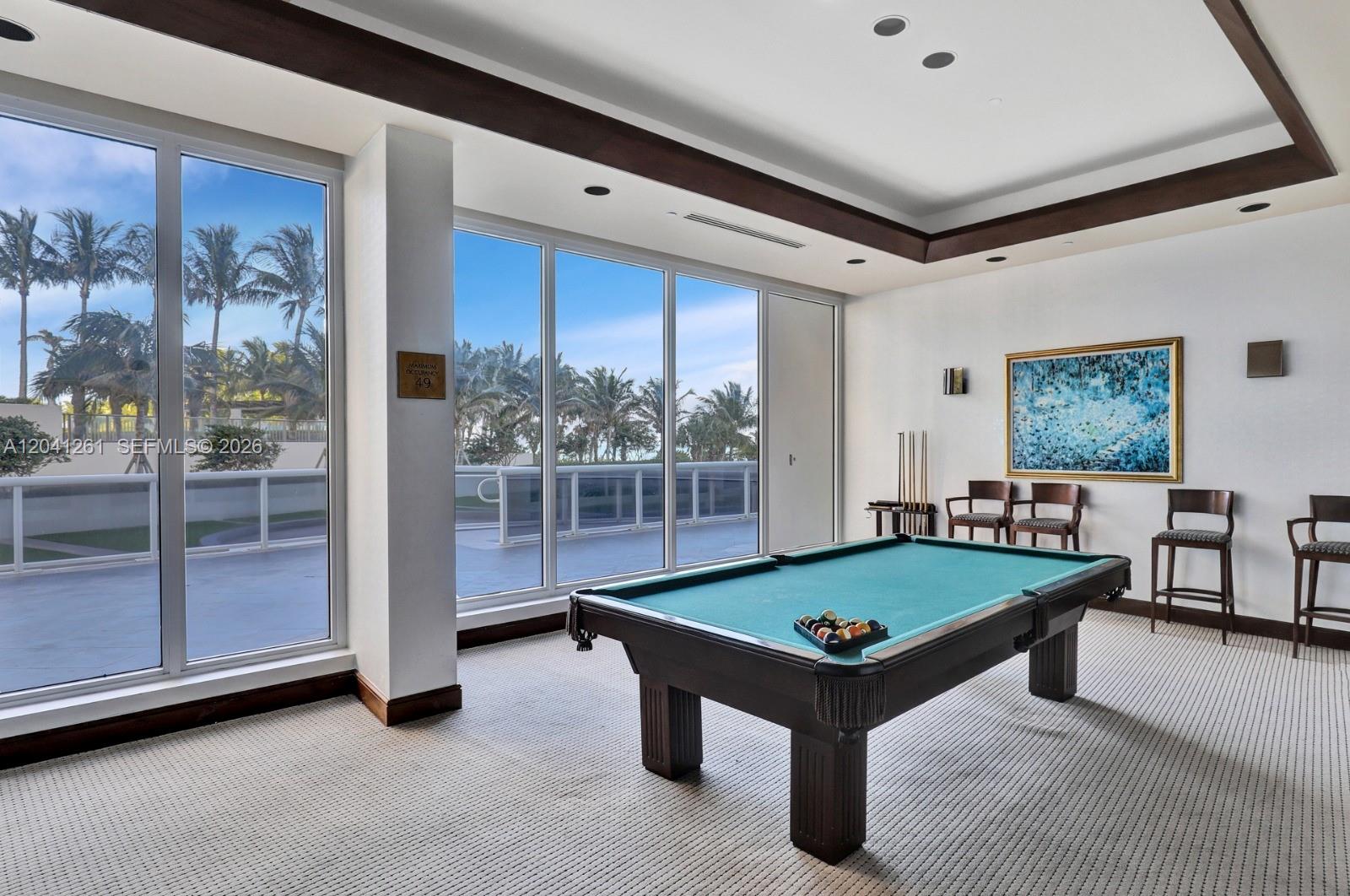 A game room features a pool table, carpeted flooring, and floor-to-ceiling windows overlooking palm trees — 9601 Collins Ave # 507, Bal Harbour FL 33154, BAL HARBOUR, FL