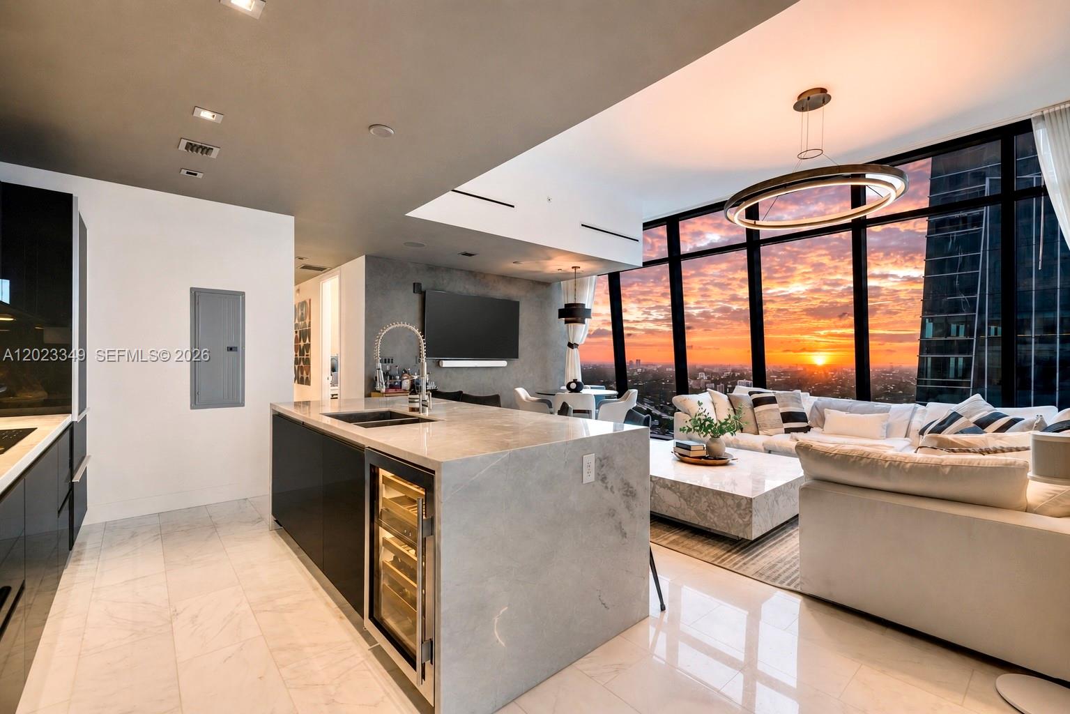 A modern kitchen island with a wine cooler sits before a living area with sunset views — 1451 Brickell Ave # 4304, Miami FL 33131, MIAMI, FL