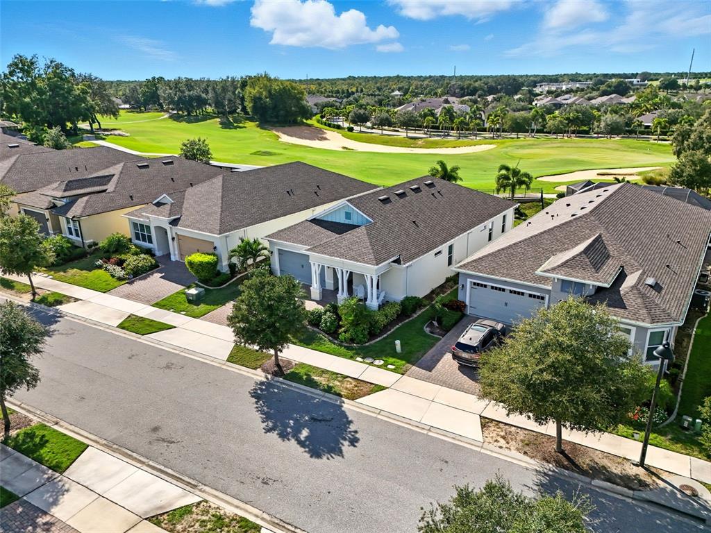 An aerial view shows several suburban houses with dark roofs situated along a golf course — 2074 FLORA PASS PLACE, KISSIMMEE, FL