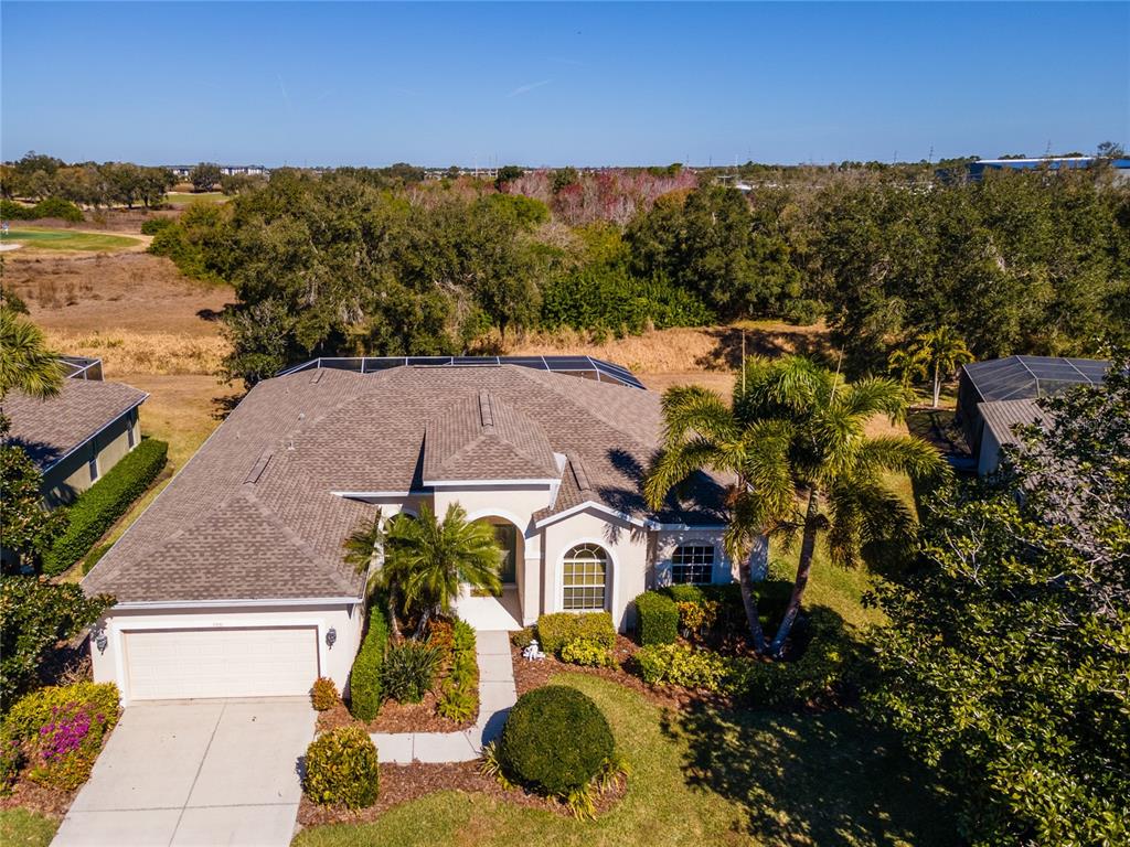 An aerial view of a single-story suburban house with a garage and screened pool enclosure — 7891 KAVANAGH COURT, SARASOTA, FL