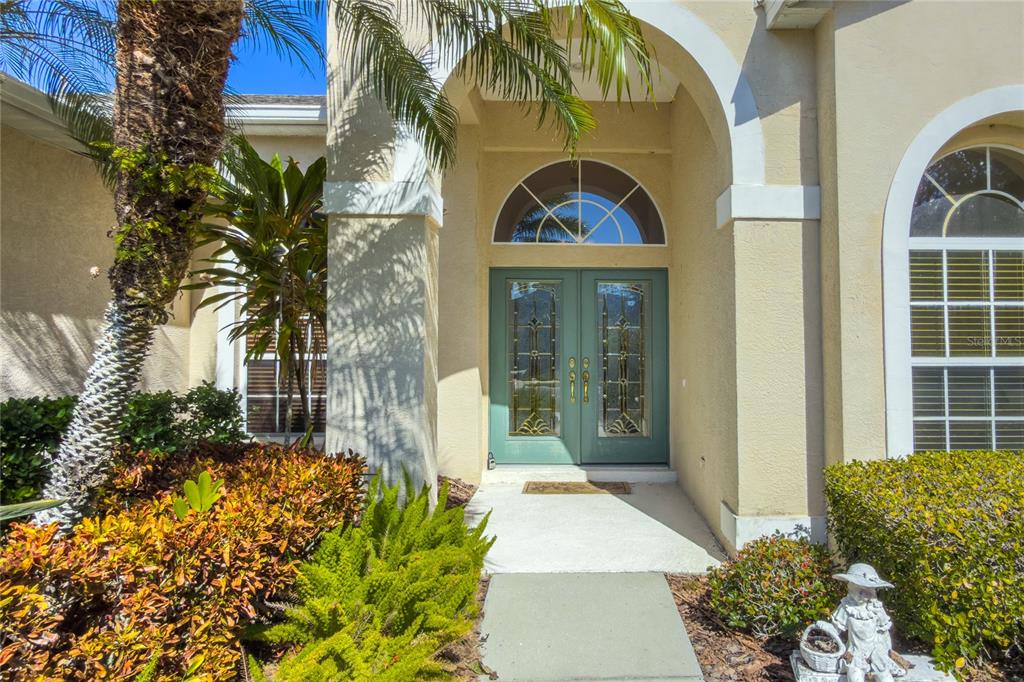 The front entrance features a double door with glass inserts under a covered arched entryway — 7891 KAVANAGH COURT, SARASOTA, FL