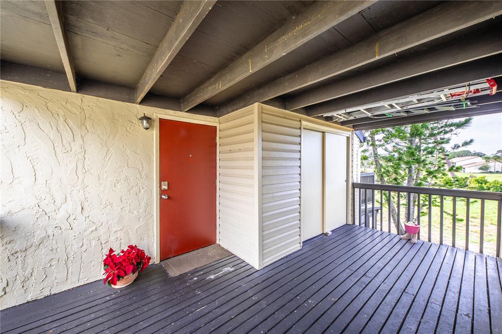 A red front door opens onto a wooden deck with a beige storage closet — 722 WHITE PINE TREE ROAD UNIT 82, VENICE, FL