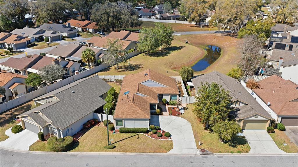 An aerial view shows three suburban houses with brown roofs, driveways, and a small pond nearby — 4427 NE 5TH STREET, OCALA, FL