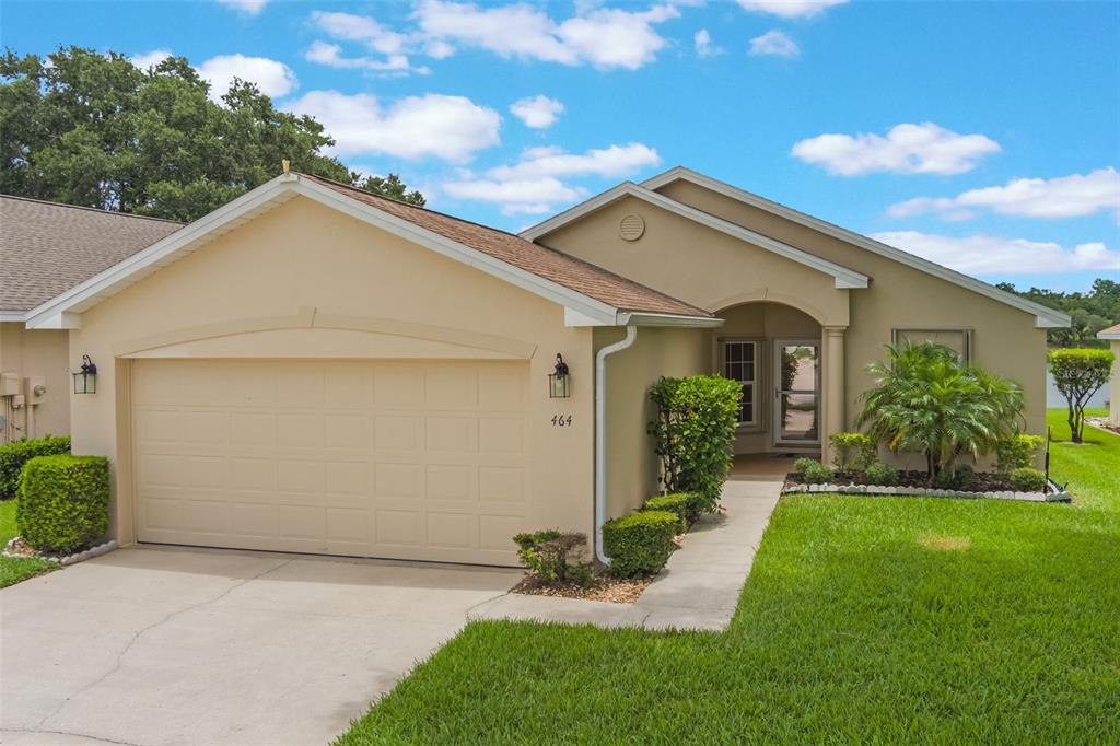 A single-story tan house with a two-car garage and a front walkway — 464 LAKE SUZANNE DRIVE, LAKE WALES, FL