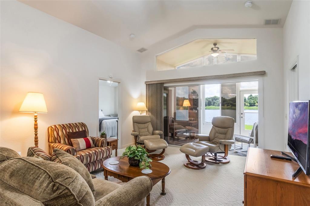A living room with vaulted ceilings, a lake view, and a sliding glass door — 464 LAKE SUZANNE DRIVE, LAKE WALES, FL
