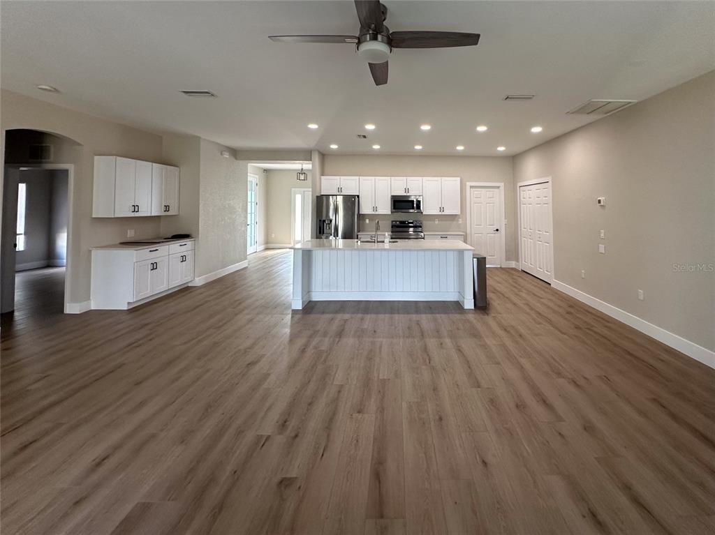 A spacious kitchen features white cabinetry, a large central island, and light wood-look flooring — 4730 LONDEL AVENUE, NORTH PORT, FL