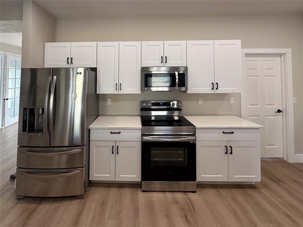 A kitchen features white cabinets, stainless steel appliances, and light-colored countertops — 4730 LONDEL AVENUE, NORTH PORT, FL