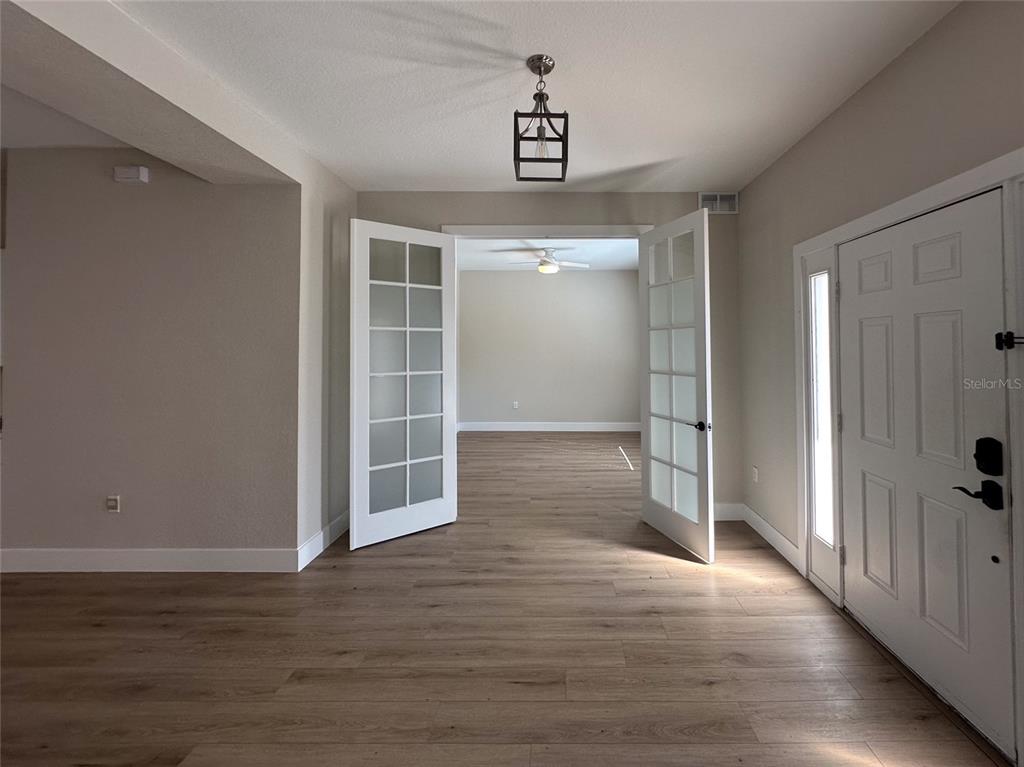 An entryway with wood-look flooring leads through French doors into a room with a ceiling fan — 4730 LONDEL AVENUE, NORTH PORT, FL