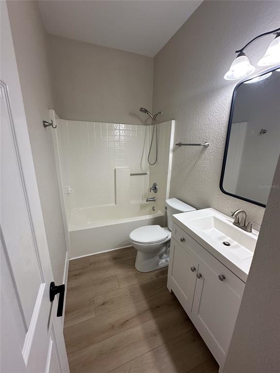 A bathroom features a white vanity, a toilet, and a shower-tub combination with light flooring — 4730 LONDEL AVENUE, NORTH PORT, FL