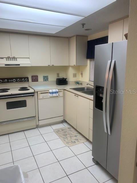 A kitchen features off-white cabinets, a white stove, a dishwasher, and a stainless steel refrigerator — 1000 BENJAMIN FRANKLIN DRIVE UNIT 205, SARASOTA, FL