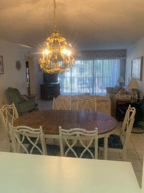 A dining area with a chandelier and table sits in front of a living room — 1000 BENJAMIN FRANKLIN DRIVE UNIT 205, SARASOTA, FL