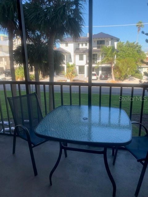 A glass-topped patio table and two chairs sit on a screened-in balcony overlooking a street — 1000 BENJAMIN FRANKLIN DRIVE UNIT 205, SARASOTA, FL