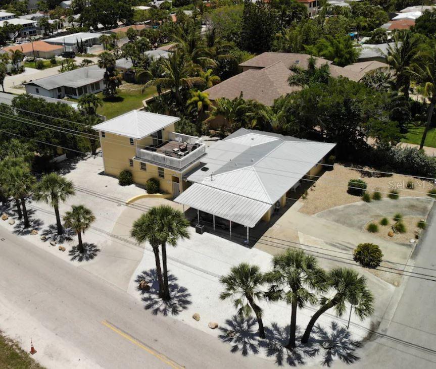 An aerial view of a yellow two-story house with a metal roof and palm trees — 301 AVENIDA MADERA UNIT B, SARASOTA, FL