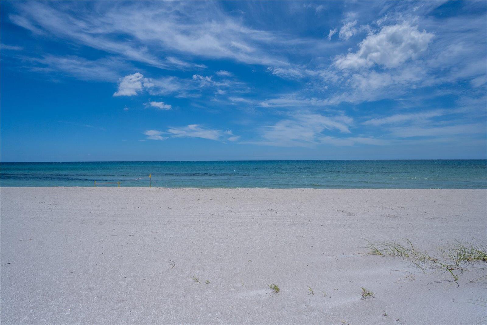 A wide, sandy beach meets the calm blue ocean under a bright, cloudy sky — 1213 S Ocean Boulevard # e, Delray Beach FL 33483, DELRAY BEACH, FL