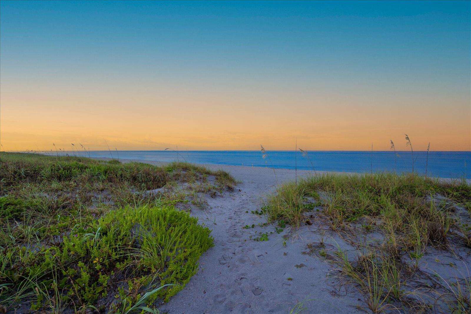 A sandy path leads through beach dunes toward the ocean under a sunset sky — 1213 S Ocean Boulevard # e, Delray Beach FL 33483, DELRAY BEACH, FL