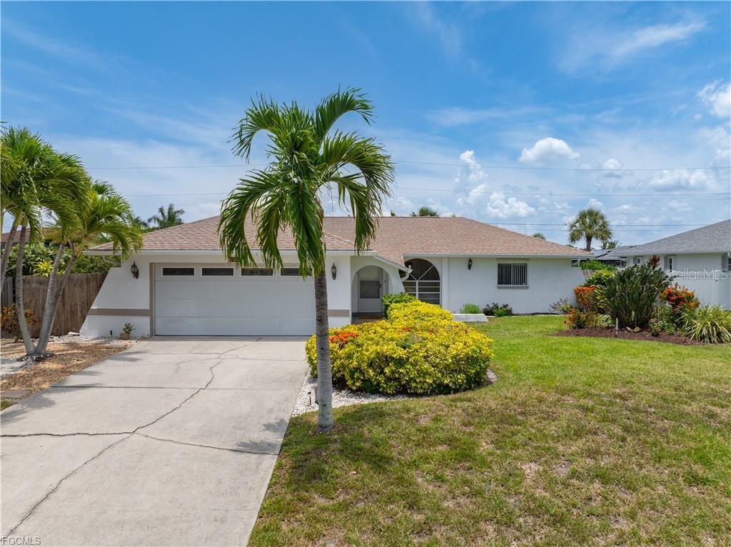 A single-story house with a white exterior, a two-car garage, and a palm tree — 1513 SW 44TH STREET, CAPE CORAL, FL