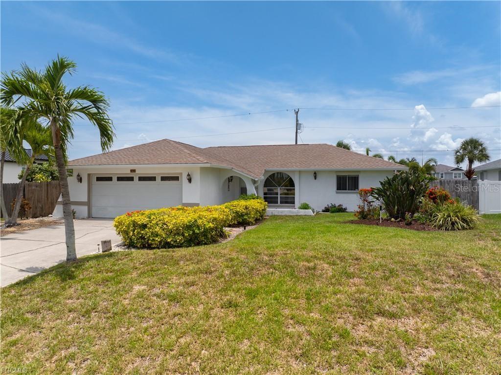 A single-story house with a white exterior, a two-car garage, and a landscaped front yard — 1513 SW 44TH STREET, CAPE CORAL, FL