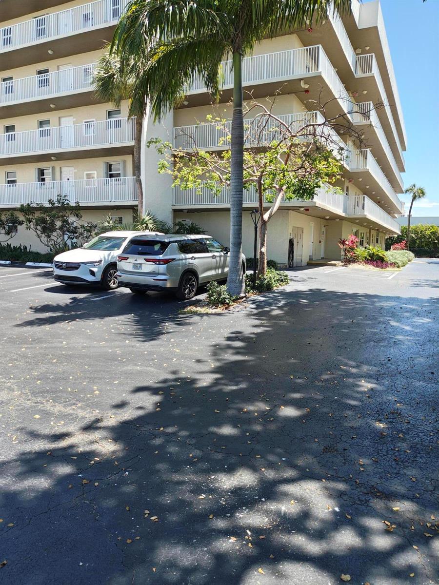 A multi-story apartment building exterior features white balconies and a parking lot with two cars — 2929 S Ocean Boulevard # 2110, Boca Raton FL 33432, BOCA RATON, FL
