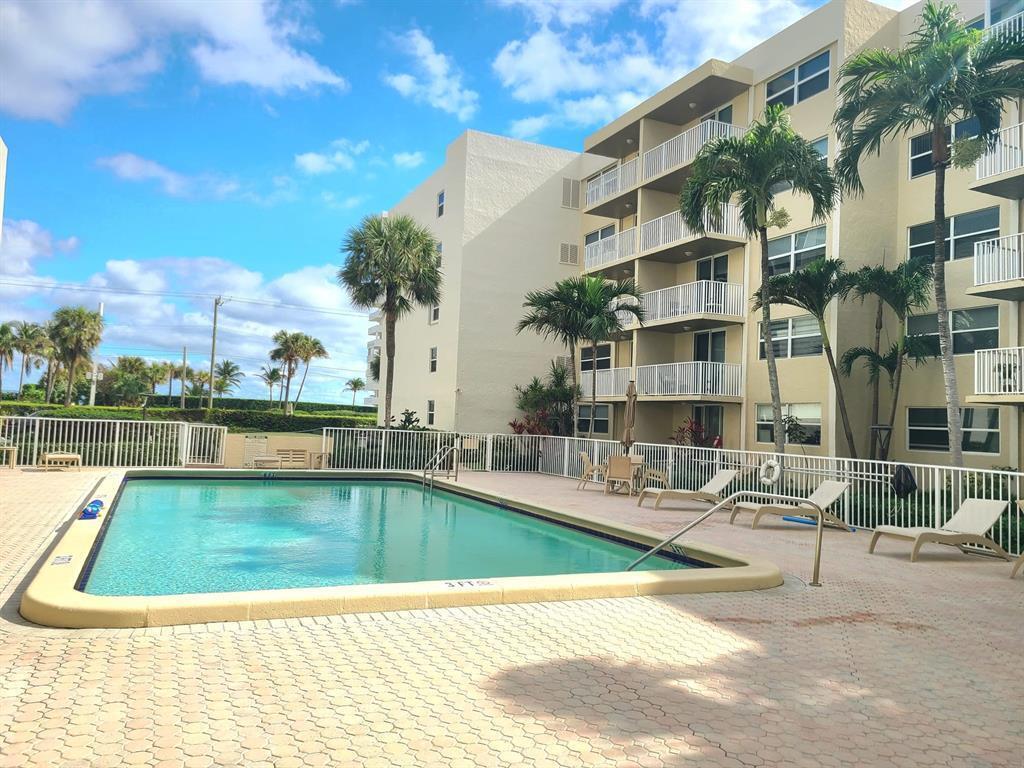 A swimming pool sits on a paved deck in front of a multi-story apartment building — 2929 S Ocean Boulevard # 2110, Boca Raton FL 33432, BOCA RATON, FL