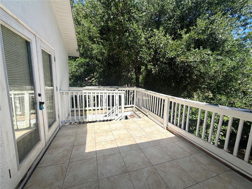 A tiled balcony features white railings and a staircase leading down to the ground level — 3510 5TH STREET SW, LEHIGH ACRES, FL